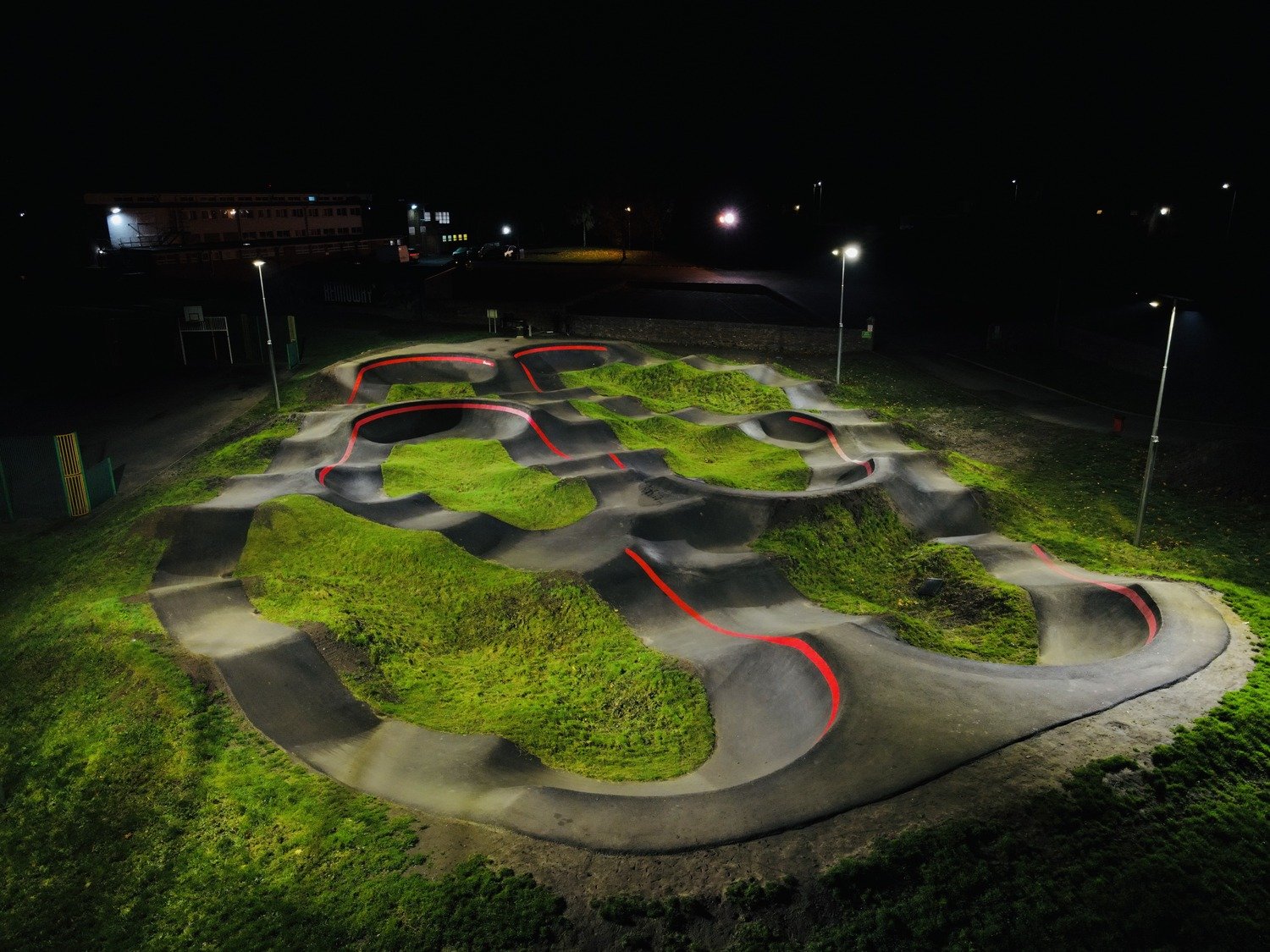 A pump track illuminated by an RM Services floodlighting installation at night